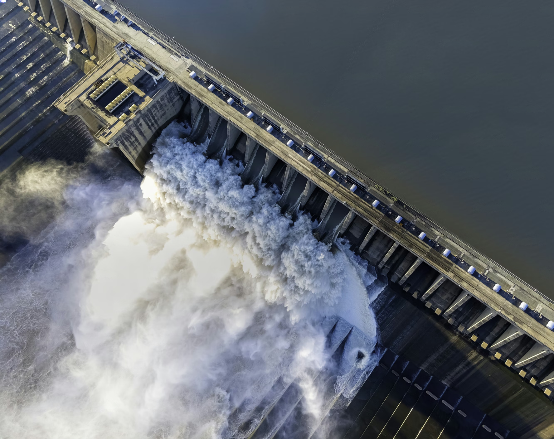 Aerial view of hydroelectric dam with rushing water demonstrating massive operational impact