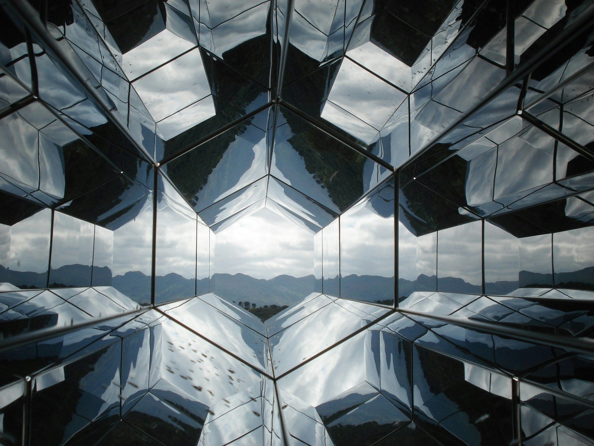 Geometric reflective glass panels with mountain landscape reflections